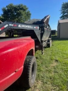 Red truck towing Ironbull dump trailer.